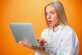 Portrait of a cheerful young teen girl holding laptop computer against orange background Royalty Free Stock Photo