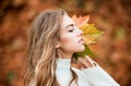 Portrait of cheerful young woman with autumn leafs in front of foliage. Royalty Free Stock Photo