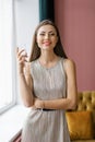 Portrait of a cheerful young woman dressed in a silver dress, holding a glass of champagne and looking at the camera in the living Royalty Free Stock Photo