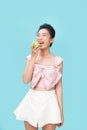 Portrait of a cheerful young woman eating green apple isolated over blue background Royalty Free Stock Photo