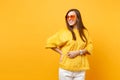 Portrait of cheerful young woman in fur sweater, white pants and heart orange glasses looking aside isolated on bright Royalty Free Stock Photo