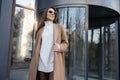 Portrait of a cheerful young woman in glasses and a brown coat outdoors. Royalty Free Stock Photo