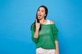 Portrait of cheerful young woman in green casual clothes showing tongue depicting heavy metal rock sign isolated on Royalty Free Stock Photo