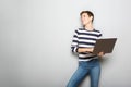 Cheerful young woman holding laptop computer against gray background Royalty Free Stock Photo