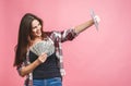 Portrait of a cheerful young woman holding money banknotes and celebrating isolated over pink background. Using tablet Royalty Free Stock Photo