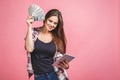 Portrait of a cheerful young woman holding money banknotes and celebrating isolated over pink background. Using tablet Royalty Free Stock Photo