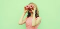 Portrait of cheerful young woman looking covering her eyes with two donuts having fun on green background Royalty Free Stock Photo