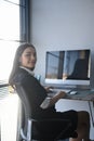 A cheerful young woman office worker sitting at her workspace and smiling to camera. Royalty Free Stock Photo