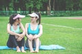 Portrait of cheerful young woman sitting on yoga mat and talking  while having break after training at stadium. Royalty Free Stock Photo