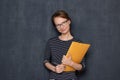 Portrait of cheerful young woman smiling and holding folder and pen Royalty Free Stock Photo