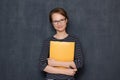 Portrait of cheerful young woman smiling and holding folder and pen Royalty Free Stock Photo