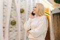 Portrait of cheerful young woman talking using mobile phone standing in hotel lounge. Smiling blonde female talking Royalty Free Stock Photo