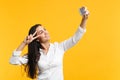 Portrait of cheerful young woman in white casual shirt showing victory sign, doing selfie shot on mobile phone isolated Royalty Free Stock Photo