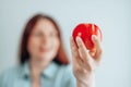 Portrait of a cheerful young woman in a white t-shirt eating red apple on gray wall background. Healthy nutrition diet Royalty Free Stock Photo