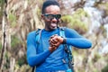 Portrait of a cheerfully smiling African-American Ethnicity young man checking a heartrate or distance on wrist smartwatch in the