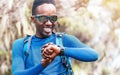 Portrait of a cheerfully smiling African-American Ethnicity young man checking a heartrate or distance on wrist smartwatch in the