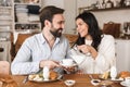 Portrait of cheery european couple drinking coffee while having breakfast in kitchen at home Royalty Free Stock Photo