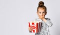 Portrait of a cheery pretty girl holding plastic cup and eating popcorn isolated over white background Royalty Free Stock Photo