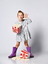 Portrait of a cheery pretty girl holding plastic cup and eating popcorn isolated over white background Royalty Free Stock Photo