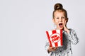 Portrait of a cheery pretty girl holding plastic cup and eating popcorn isolated over white background Royalty Free Stock Photo