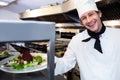 Portrait of a chef handing dinner plate through order station