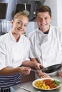 Portrait Of Chef Instructing Female Trainee In Restaurant Kitchen Royalty Free Stock Photo