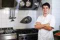 Portrait Of Chef Wearing Whites Standing By Cooker In Kitchen