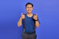 Portrait of cherful Asian man showing thumbs up or sign of approval isolated on purple background Royalty Free Stock Photo