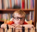 Portrait, chess and boy with glasses, bored and competition with training, skills and clear vision. Face, person or kid