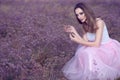 Portrait of chic woman with provocative make up and long hair sitting in the field of violet flowers.