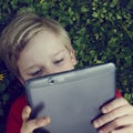 Portrait of Child blond young boy playing with a digital tablet Royalty Free Stock Photo