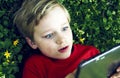 Portrait of Child blond young boy playing with a digital tablet Royalty Free Stock Photo