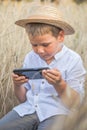 Portrait of child boy playing online games with smartphone, sitting outdoor play with phone in hand in wheat field Royalty Free Stock Photo