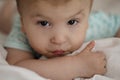 Portrait of a child with cerebral palsy lying on his belly. Special needs child face looking at the camera with thumb up.