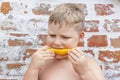 Portrait of child. Cute boy posing and eating a delicious orange. The emotions of a child