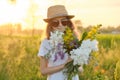 Portrait of child girl in hat sunglasses with flowers in meadow Royalty Free Stock Photo
