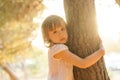 Portrait of child girl hugging the tree on the background of park Royalty Free Stock Photo