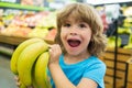 Portrait of child in grocery shopping in supermarket, kid shopping for fresh banana in supermarket. Royalty Free Stock Photo