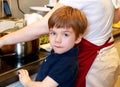 Portrait of child in kitchen. Cute little boy, playing in kitchen. Young kid is hungry, looks at and checks is it finished lunch.