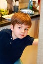 Portrait of child in kitchen. Cute little boy, playing in kitchen. Young kid is hungry, looks at and checks is it finished lunch.