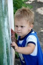 Portrait of child. Little boy focused, trying to open the door. Outdoor. Royalty Free Stock Photo