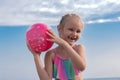 Portrait of a child, a little girl, blonde in a swimsuit on the beach, playing with a ball, six years old, Royalty Free Stock Photo