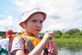 Portrait of a child in an orange life jacket blowing soap bubbles floating on a boat with his parents. Royalty Free Stock Photo