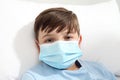 Portrait of child with protective blue mask lying in bed, corona virus covid 19 protection concept