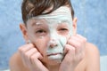 Portrait of child teen boy removing alginate mask from face looking at camera. Royalty Free Stock Photo