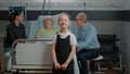 Portrait of child visiting senior woman in hospital ward with mother