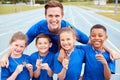 Portrait Of Children With Male Coach Showing Off Winners Medals On Sports Day Royalty Free Stock Photo