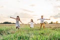 Portrait of children playing game of catch and running, jumpimg on grass hay field paths of dry grass in the sunrise. Royalty Free Stock Photo