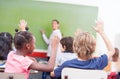 Portrait of children raised their hands in a multi ethnic classroom Royalty Free Stock Photo