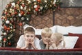 Portrait of children siblings on bed on Christmas decorations background. Older brothers and little sister in bedroom Royalty Free Stock Photo